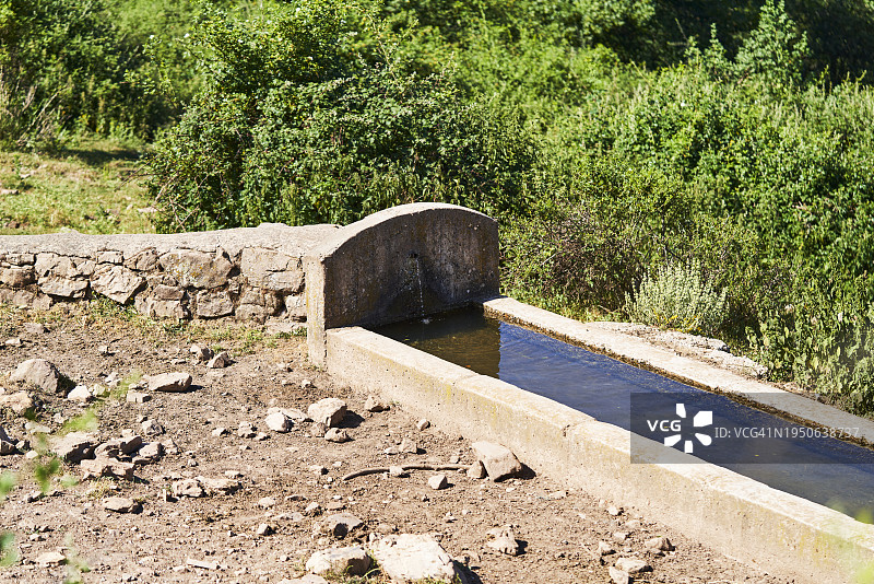 农场牲畜饮水池的正面图，周围是草地，没有人图片素材