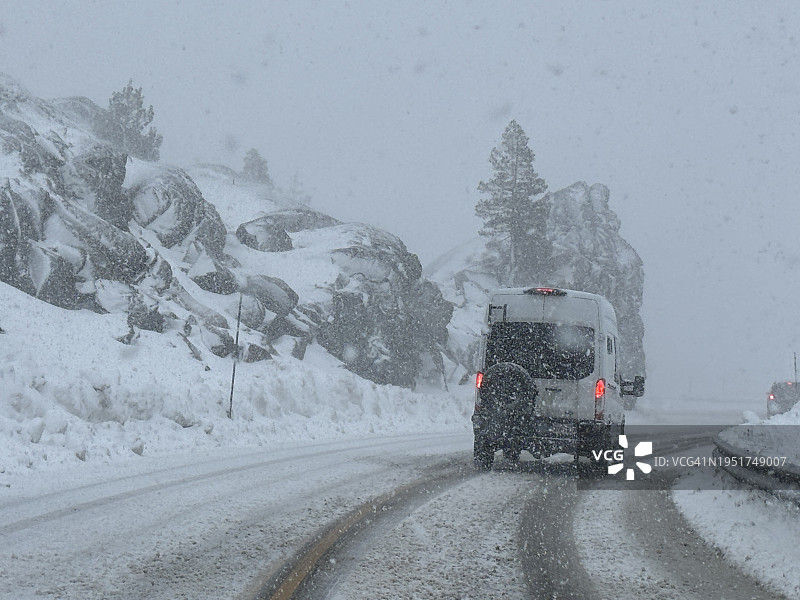 白色厢型车行驶在加利福尼亚州唐纳峰冰雪路面上图片素材
