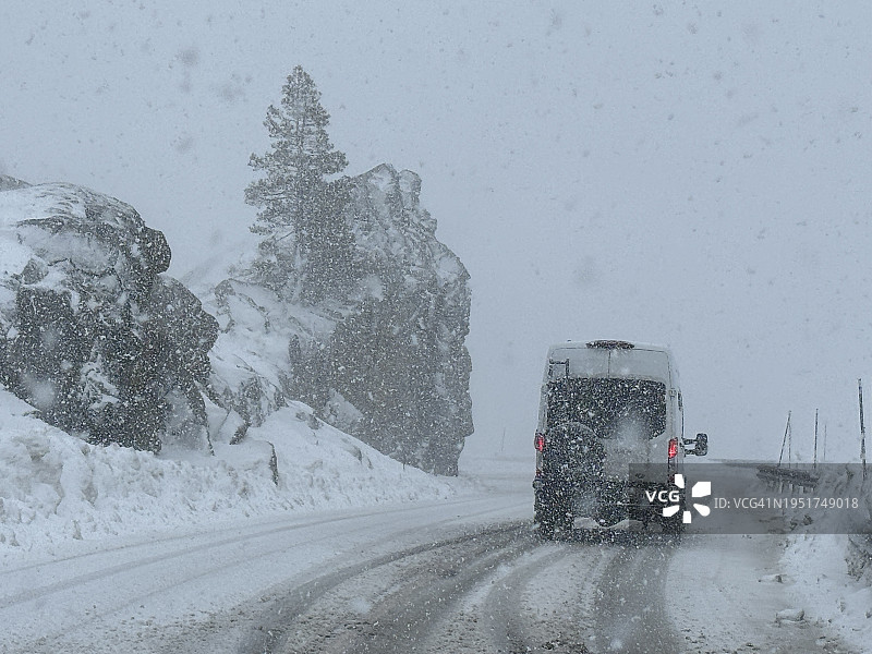白色厢型车行驶在加利福尼亚州唐纳峰冰雪路面上图片素材