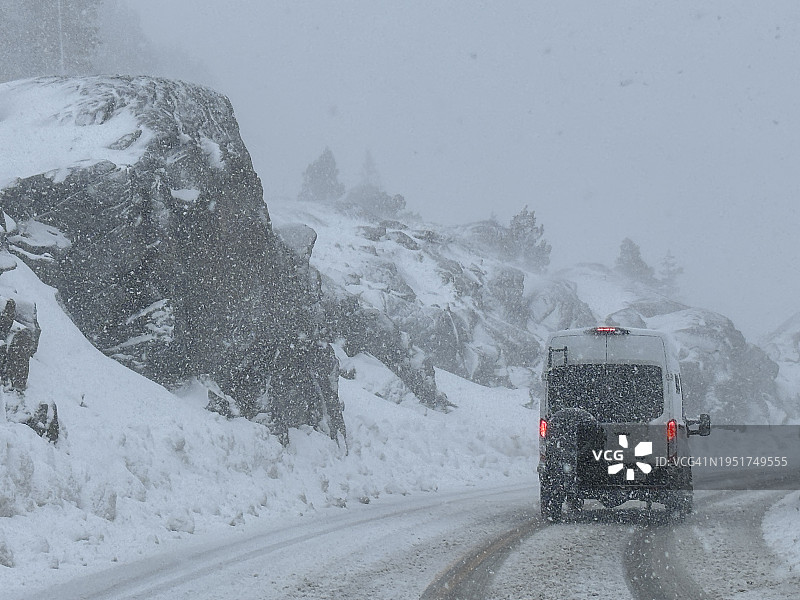 白色厢型车行驶在加利福尼亚州唐纳峰冰雪路面上图片素材
