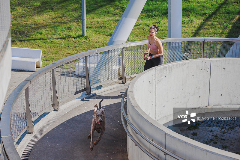 在城市车库高架人行道上和她的狗一起跑步图片素材