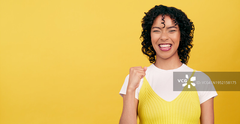成功喜悦：举拳庆祝的女子（黄色背景）图片素材