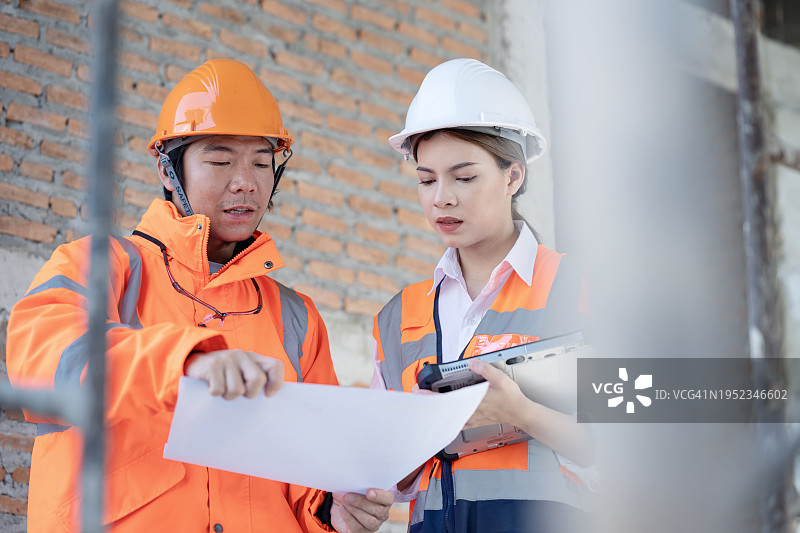 建筑项目质量管理提升运营效率和降低成本。男女建筑工程师讨论项目计划数据，以估算施工阶段的项目成本和资源。图片素材