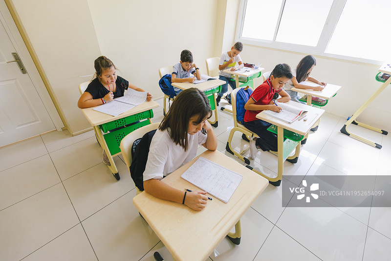 专注的小学生在教室的课上坐在书桌旁写作图片素材