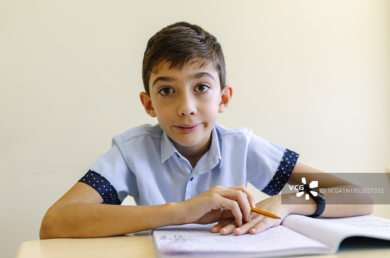 快乐的男学生坐在教室的课桌旁肖像图片素材