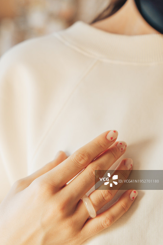女士手戴戒指，做过美甲，背景为白色外套图片素材