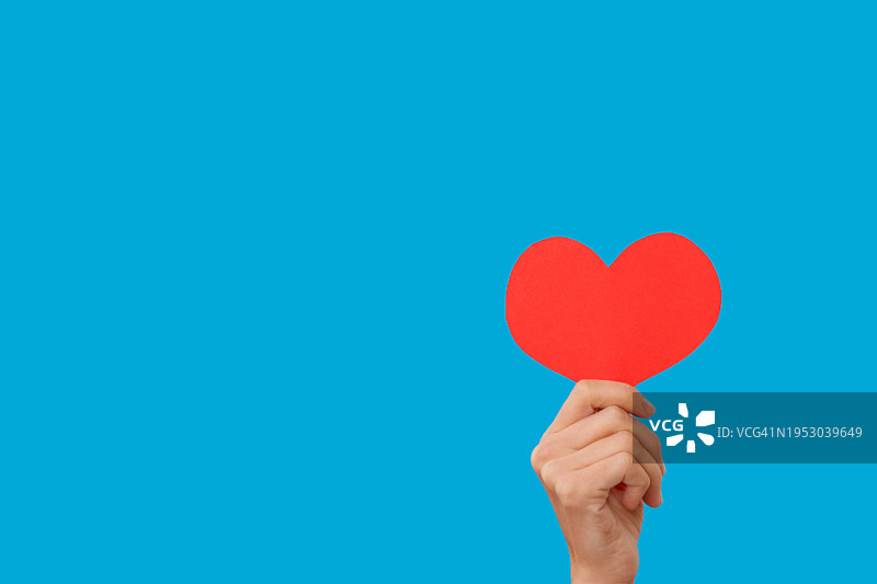 拿着心形物的手（蓝色背景）图片素材