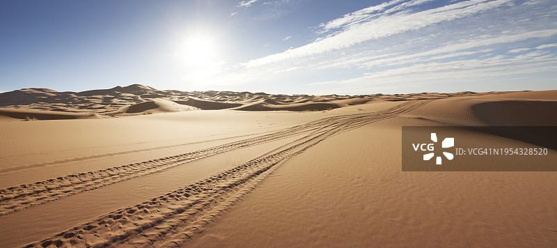 晴空下沙漠沙丘中的轮胎痕迹图片素材
