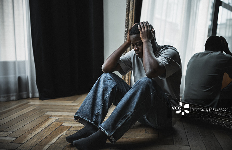 沮丧、孤独和情绪压力时刻。年轻黑人男子坐在地上，看起来非常沮丧和有压力图片素材