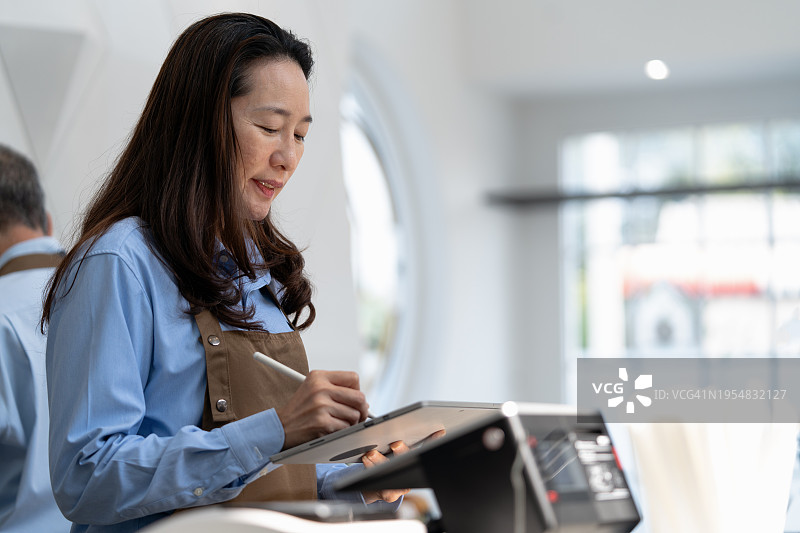 咖啡店主使用平板电脑回复客户在线订单，对大量涌入的订单感到高兴图片素材