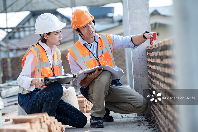材料检验和测试，确保建筑项目的质量和安全，女性项目负责人和男性工程师在施工阶段使用水平仪测量砖墙，以达到合理的标准图片素材