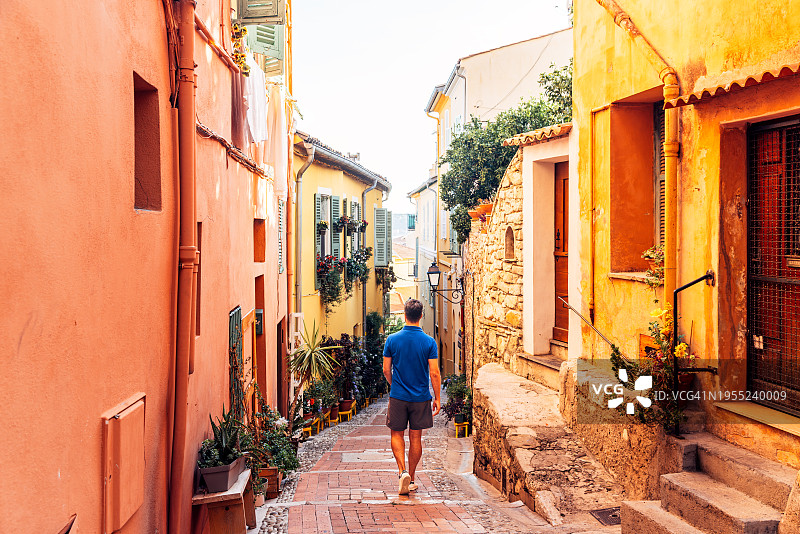 一名男子在法国里维埃拉芒通老城的狭窄小巷中探索的后视图图片素材
