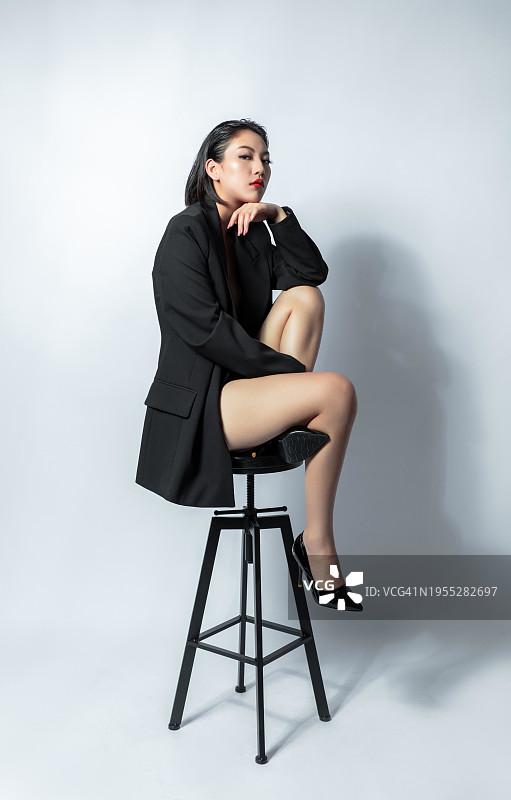 身穿黑色西装坐在凳子上的优雅亚洲女性图片素材