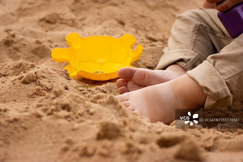 沙滩上晒黑的婴儿脚，附近有沙模图片素材