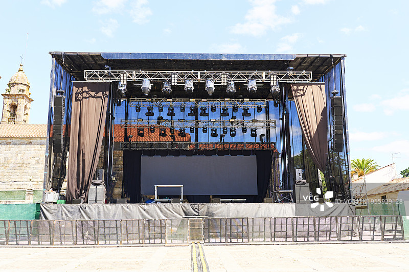 户外音乐会金属舞台的正面图，有空座位，背景有人图片素材