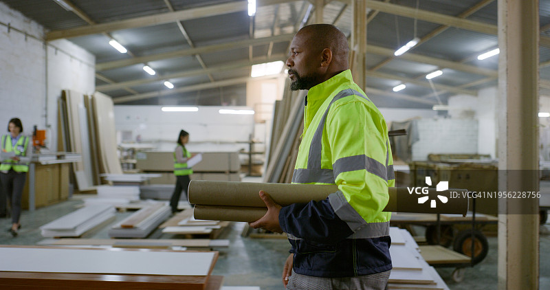 男子，工程师，拿着建筑蓝图，解决建筑问题、建筑设计或开发问题。仓库里，男子拿着施工计划，作为项目承包商，负责协议、维护或翻新工作图片素材