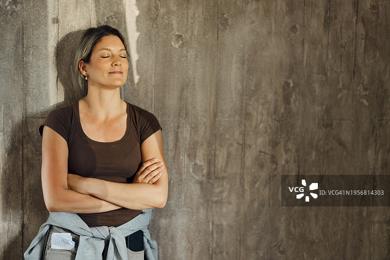 年轻微笑的女子靠墙抱臂图片素材