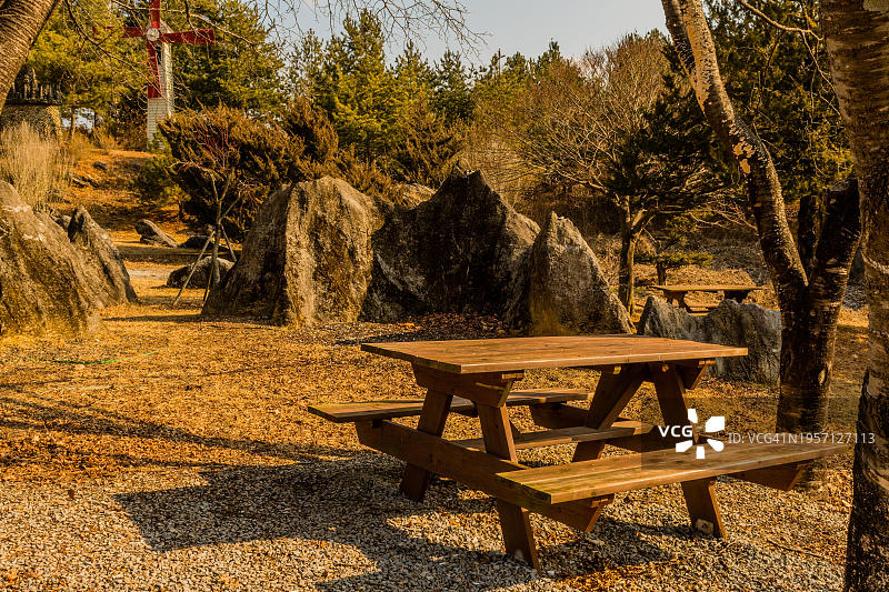 韩国乡村路边公园的大花岗岩巨石前的木制野餐桌图片素材