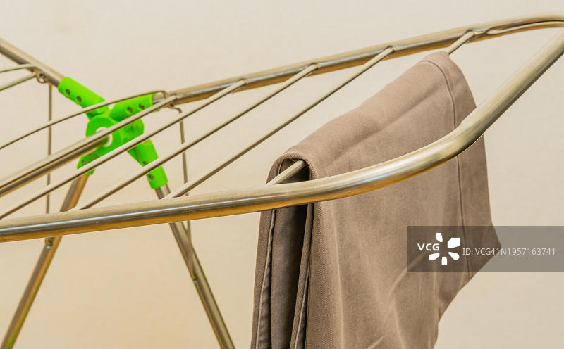 整齐地挂在折叠晾衣架上的一条棕色休闲裤，韩国，亚洲图片素材