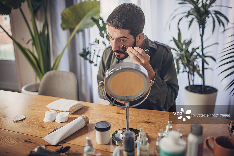 男人在家用玉石滚轮按摩面部图片素材