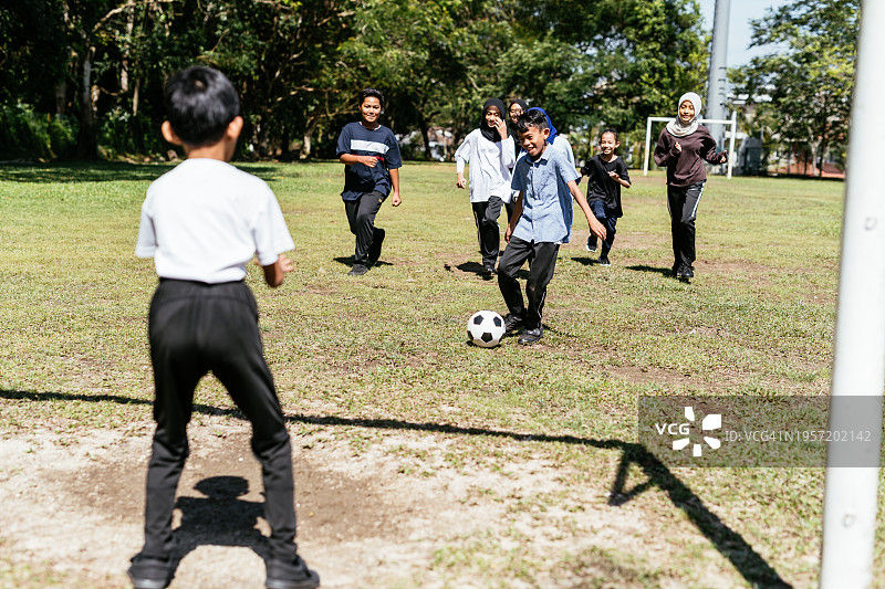 小学生在校园里踢足球图片素材