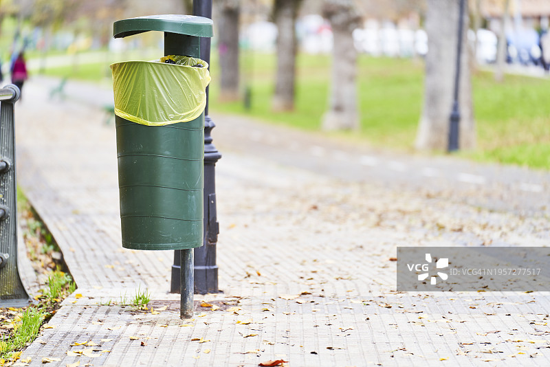 公园小路上放置的塑料垃圾桶，背景是草地和树木图片素材