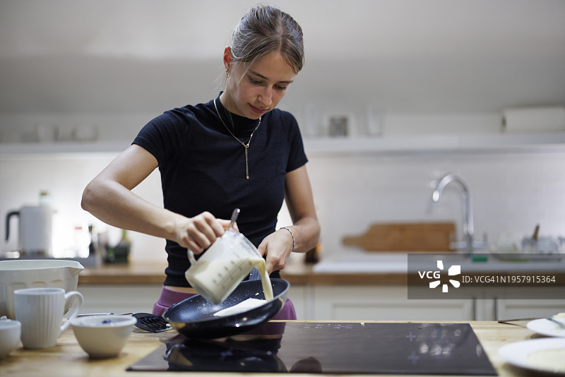 青少年女孩在厨房准备午餐的薄煎饼图片素材