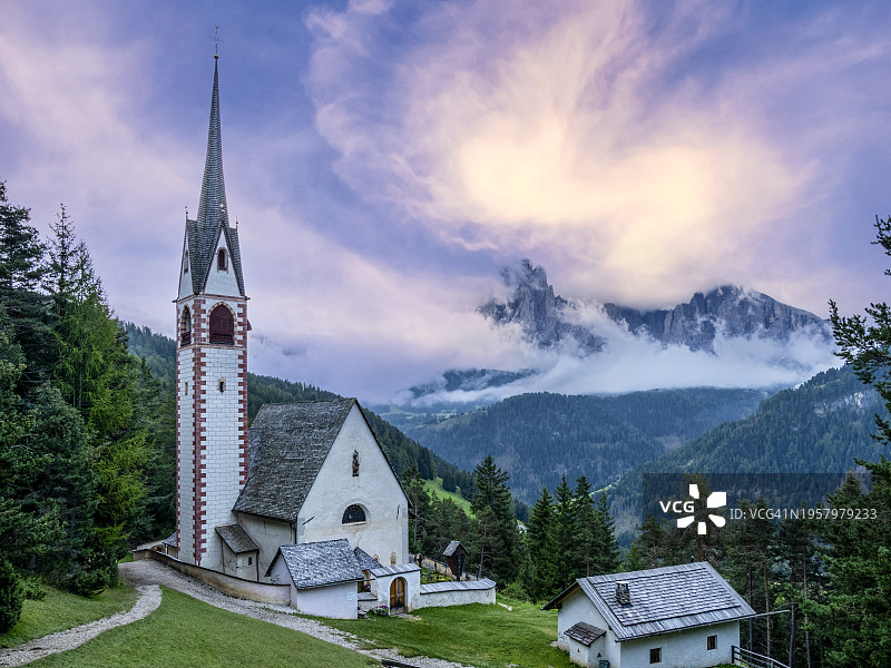 多洛米蒂阿尔卑斯山日落时分的高山景观，山谷中有一座典型的教堂图片素材