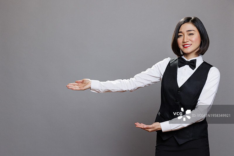 在灰色背景下手势的微笑年轻女商人肖像图片素材