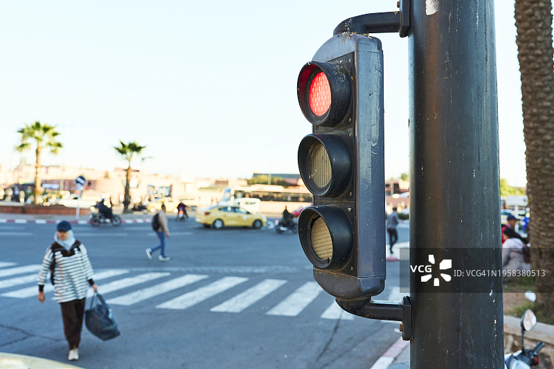城市街道上红灯交通信号灯的侧面照，背景中有人穿过图片素材