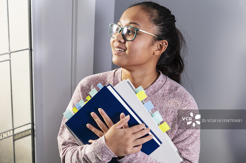 手持带书签的教科书的亚洲女性图片素材