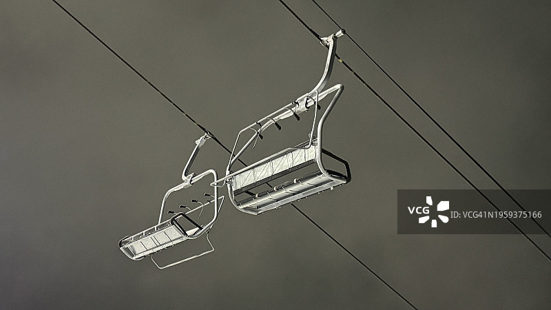 加利福尼亚州苏打泉市北极星滑雪胜地：夜间滑雪场金属缆车在黑暗的天空中被明亮的光照亮，雾气蒙蒙图片素材