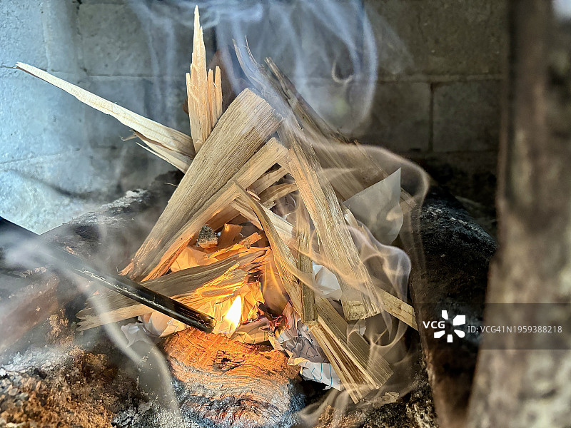 用打火机点燃壁炉中的木柴，引燃引火物，呈现黄色和橙色火焰图片素材