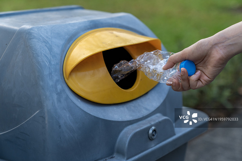 年轻女人的手在公园里将塑料瓶扔进垃圾桶图片素材