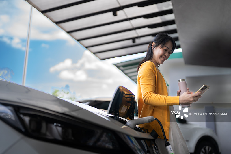 女子在家等待电动汽车充电图片素材