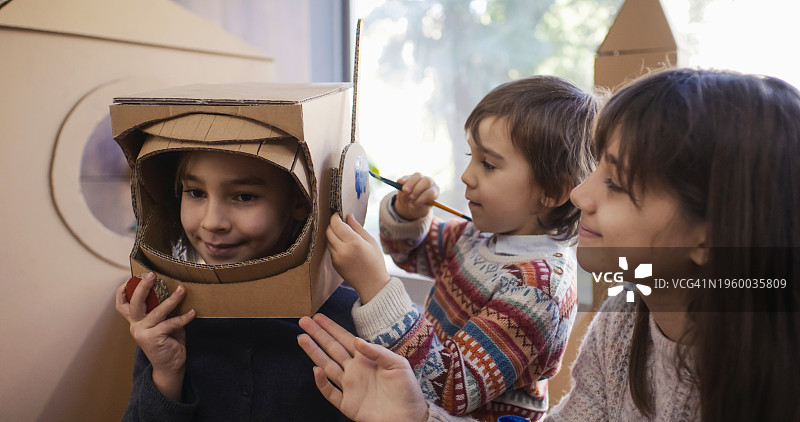 孩子们在家里做手工，绘制纸板太空头盔图片素材