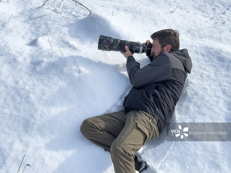 摄影师躺在雪地上用相机拍照图片素材