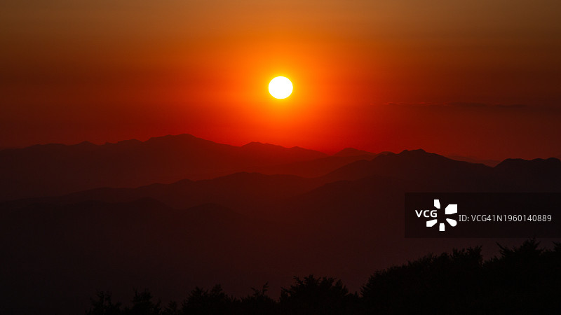 橙色天空映衬下群山剪影的美景图片素材