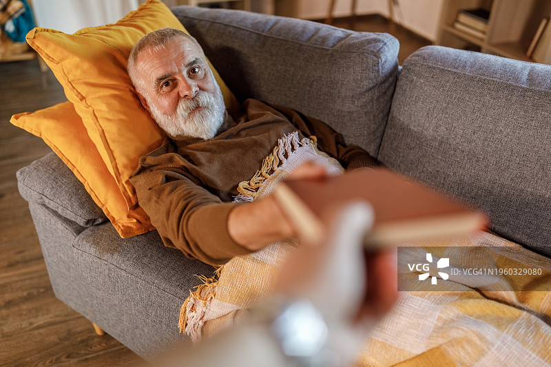 男人对着镜头微笑并伸手拿书图片素材