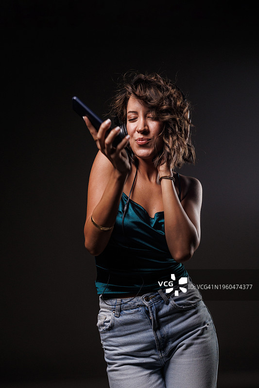 戴着耳机跳舞听她最喜欢的歌曲的快乐年轻女人图片素材