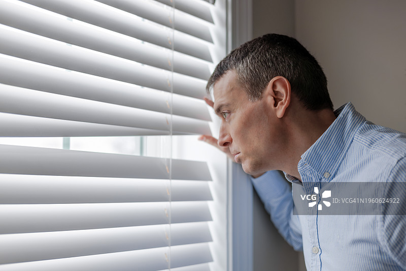 男人透过百叶窗向外看图片素材