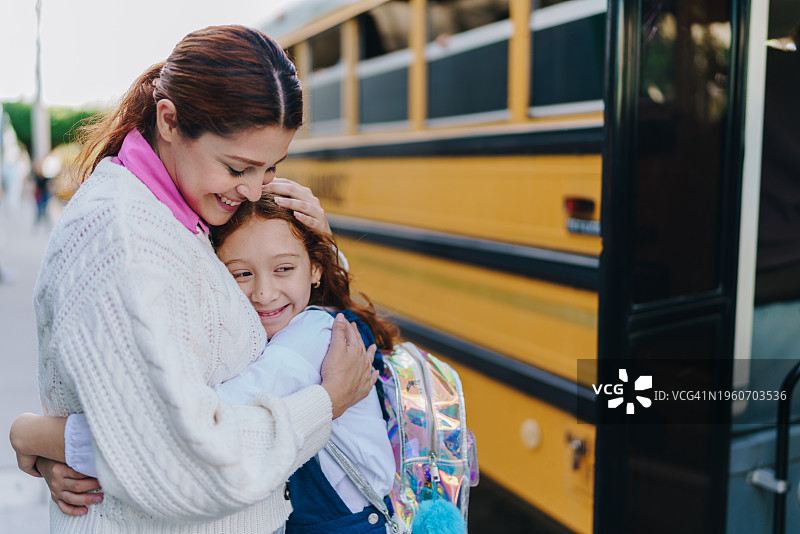 儿童学生在街上上校车前拥抱母亲图片素材