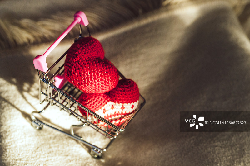 浅色背景上带有针织红心的购物车，情人节图片素材