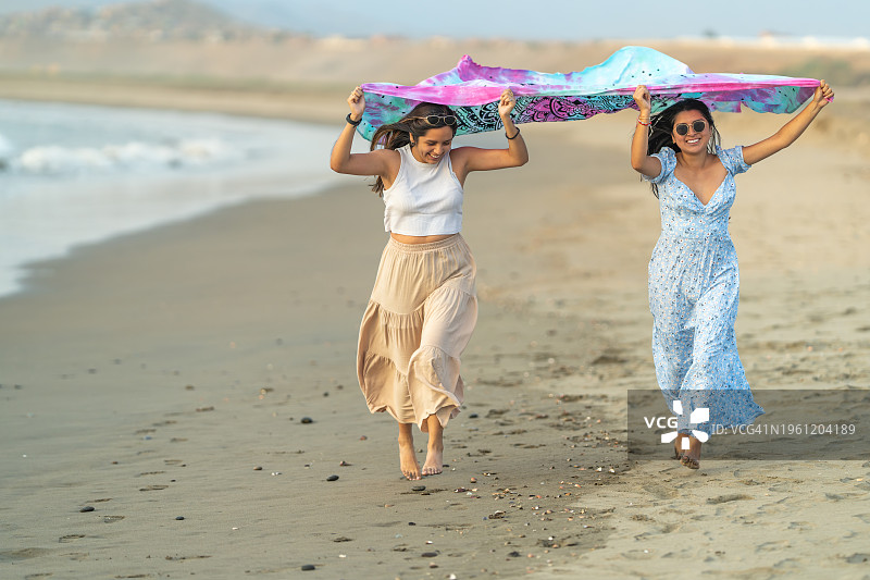 在海边裹着纱笼奔跑的女孩们图片素材