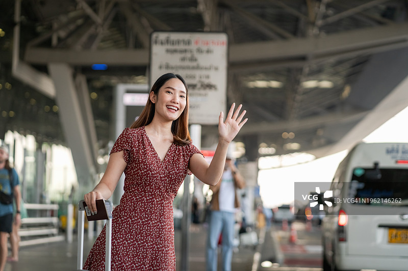 在机场招出租车回家的年轻亚洲女性图片素材