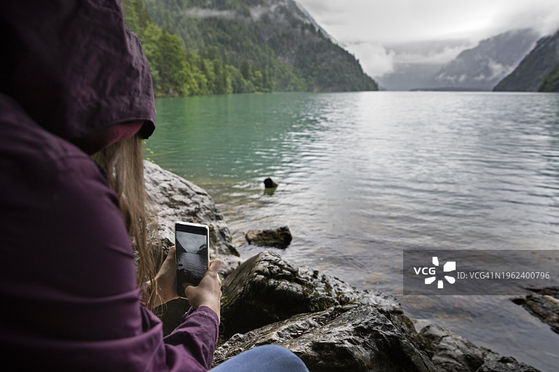 青少年蹲在湖边，用手机拍照图片素材