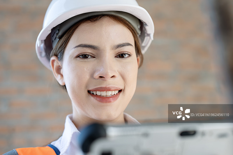 在建筑行业中建立性别平等的基础。一位女性建筑工程师在建筑工地工作，使用平板电脑管理建筑项目和制定建筑计划的肖像。图片素材