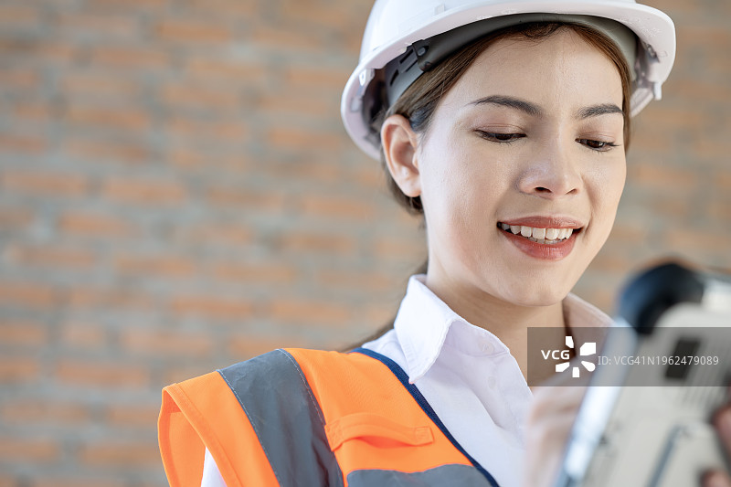 建筑行业高效项目管理中改进的预算控制和明智的决策：女工程师在建筑工地使用平板电脑跟进项目任务图片素材