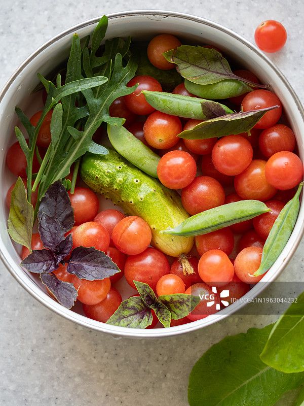 新鲜有机蔬菜混合沙拉碗俯视图，含樱桃番茄、黄瓜、罗勒叶、青豆和芝麻菜图片素材