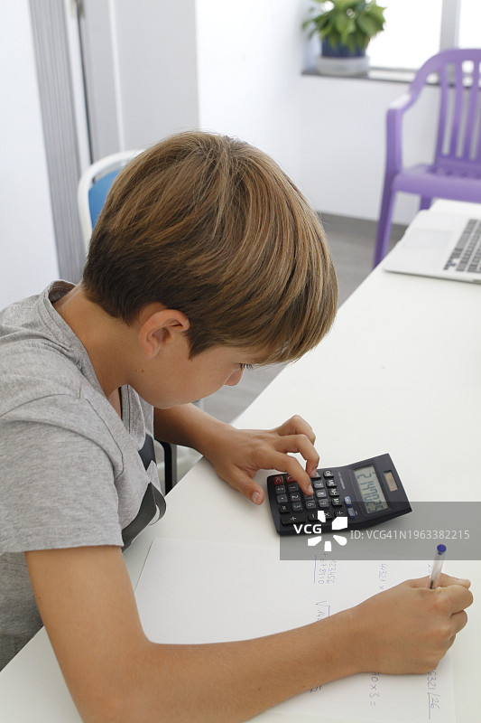 男孩用计算器解决数学题图片素材